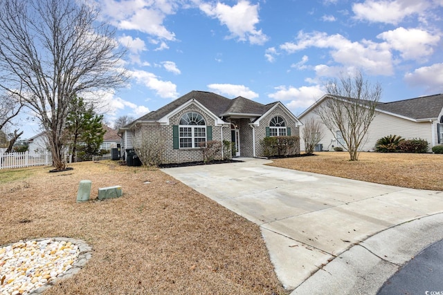 single story home featuring driveway, brick siding, and fence