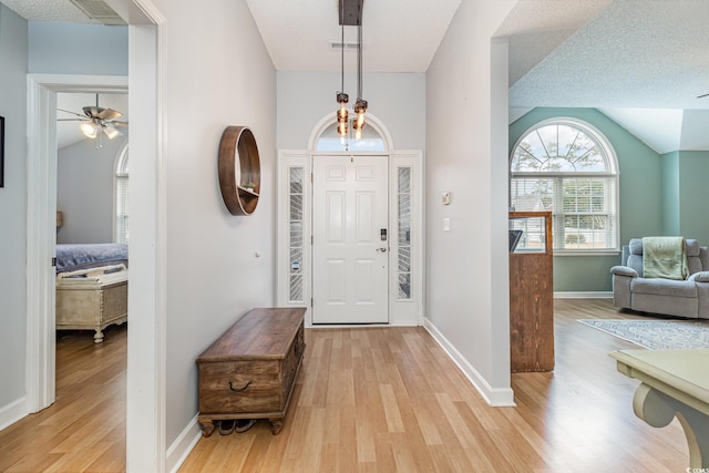 entrance foyer featuring a ceiling fan, light wood-type flooring, visible vents, and vaulted ceiling