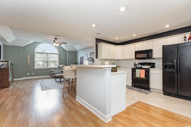 kitchen featuring lofted ceiling, black appliances, open floor plan, and backsplash