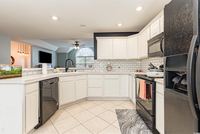 kitchen featuring light tile patterned floors, a peninsula, a sink, black appliances, and backsplash