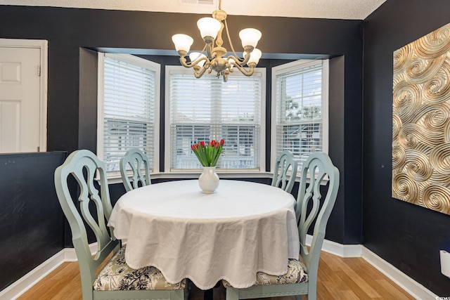 dining space featuring visible vents, light wood-style flooring, baseboards, and an inviting chandelier