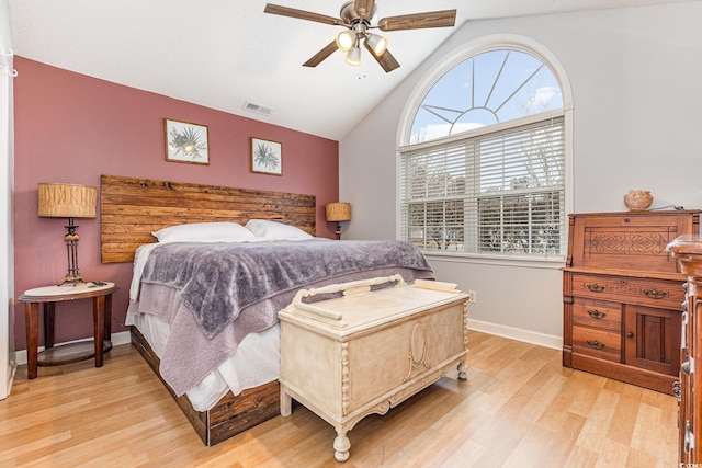 bedroom featuring lofted ceiling, a ceiling fan, baseboards, visible vents, and light wood-style floors