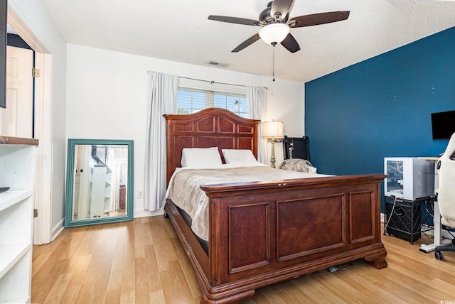 bedroom featuring a textured ceiling, ceiling fan, light wood-type flooring, and visible vents