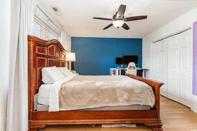 bedroom featuring a closet, visible vents, a ceiling fan, a textured ceiling, and wood finished floors