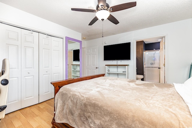 bedroom featuring a closet, a ceiling fan, a textured ceiling, ensuite bath, and wood finished floors