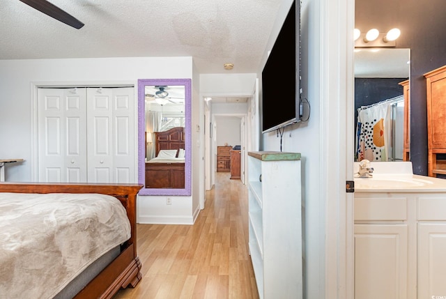 bedroom featuring a textured ceiling, a closet, light wood-type flooring, and a sink