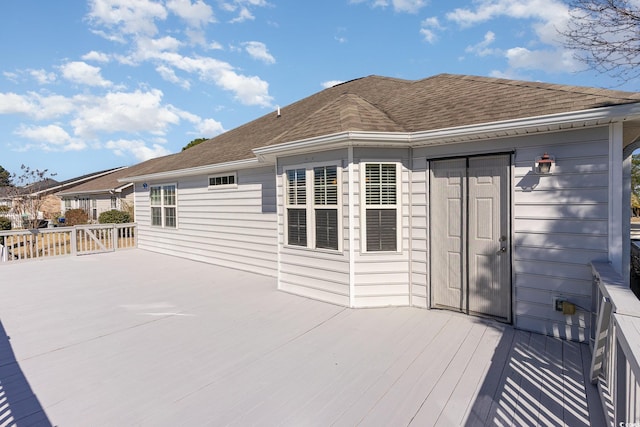 back of property with roof with shingles and a wooden deck