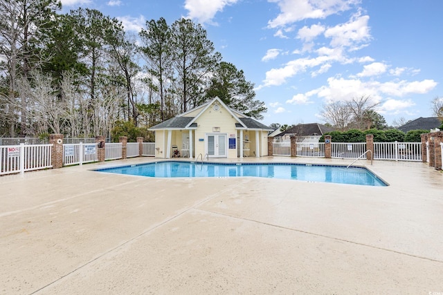 community pool featuring an outbuilding, a patio area, fence, and a storage structure