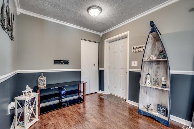 interior space featuring wood-type flooring, ornamental molding, and a textured ceiling