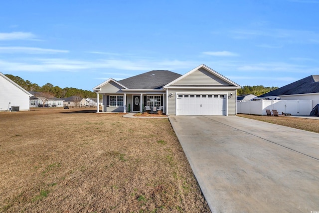 ranch-style house featuring a front yard, fence, driveway, covered porch, and a garage