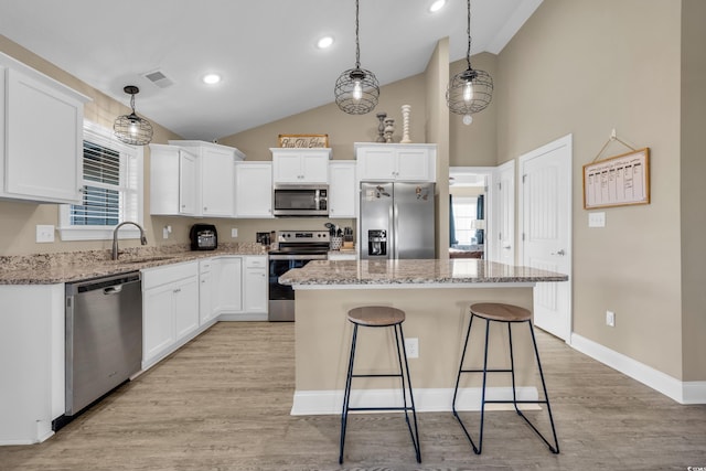 kitchen featuring visible vents, a sink, a kitchen island, white cabinetry, and stainless steel appliances