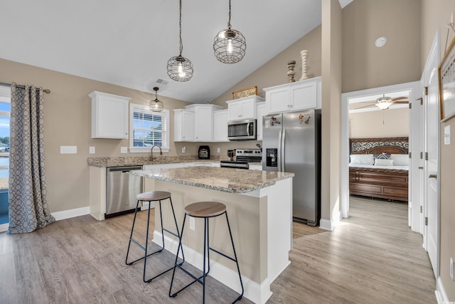 kitchen featuring a center island, light wood-style flooring, stainless steel appliances, and a kitchen bar