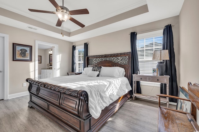 bedroom featuring visible vents, a raised ceiling, light wood-style floors, and baseboards