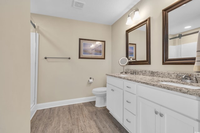 bathroom with visible vents, toilet, a sink, wood finished floors, and baseboards