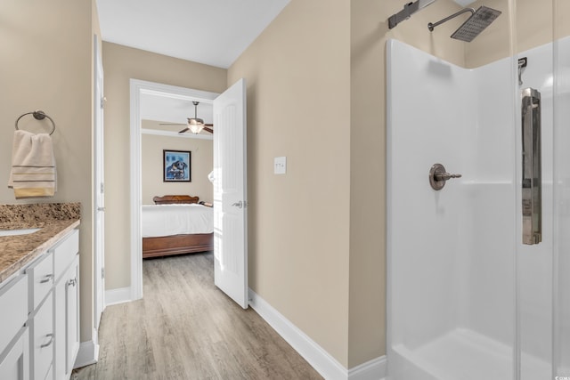 full bath featuring vanity, wood finished floors, baseboards, a stall shower, and ceiling fan