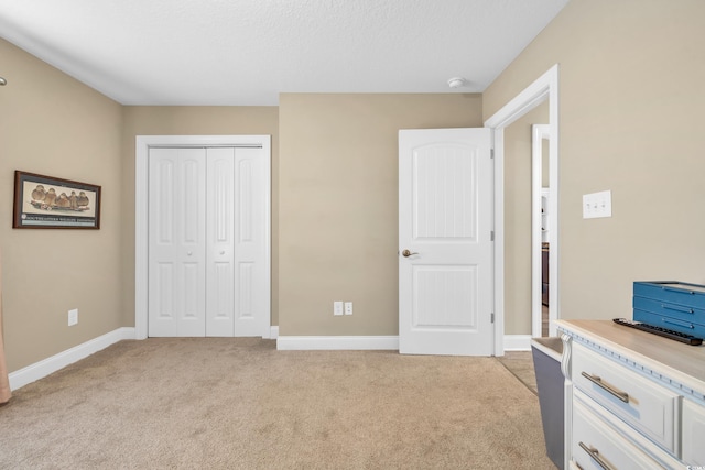 bedroom with a closet, light colored carpet, and baseboards