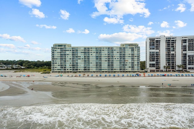 view of building exterior with a water view and a beach view