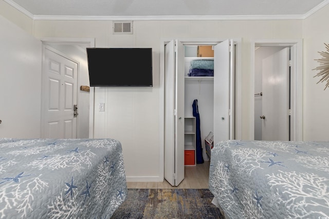 bedroom with crown molding, dark hardwood / wood-style flooring, and a closet