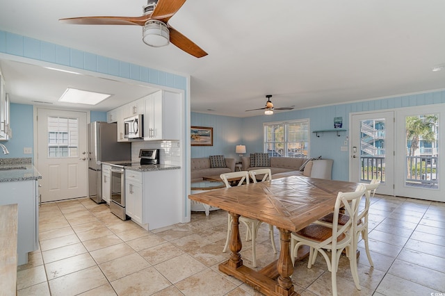 tiled dining space with plenty of natural light, sink, and ceiling fan