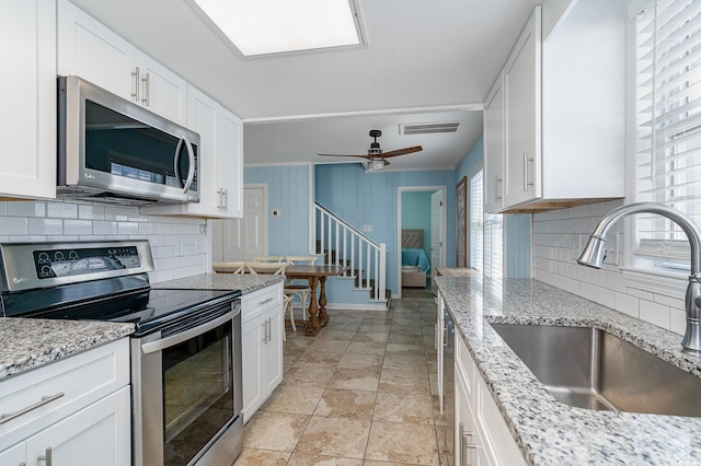 kitchen featuring white cabinetry, stainless steel appliances, light stone countertops, and sink