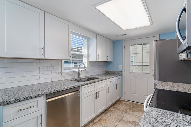 kitchen with appliances with stainless steel finishes, tasteful backsplash, white cabinetry, sink, and light stone countertops