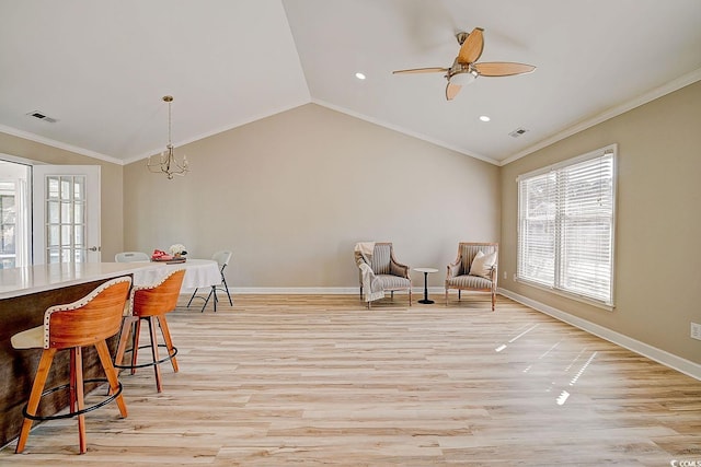 living area featuring crown molding, vaulted ceiling, ceiling fan with notable chandelier, and light hardwood / wood-style flooring