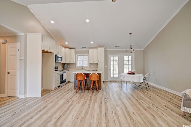 kitchen with a kitchen island, white cabinetry, appliances with stainless steel finishes, and a kitchen breakfast bar