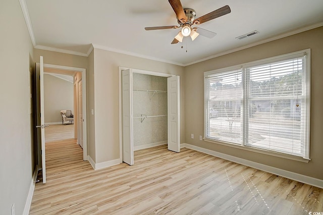 unfurnished bedroom featuring crown molding, light hardwood / wood-style flooring, a closet, and ceiling fan