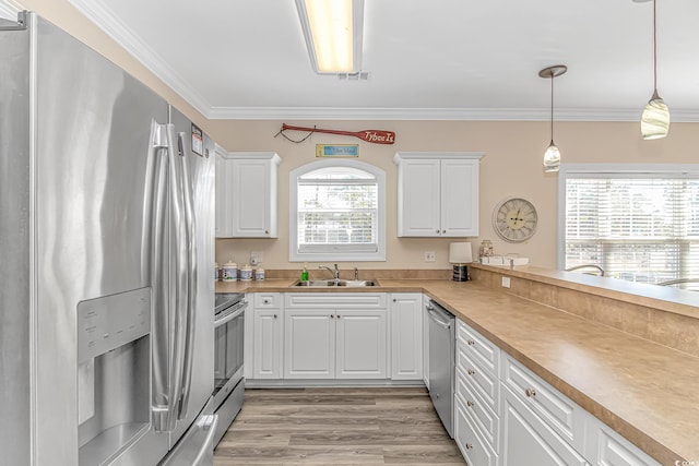 kitchen with white cabinetry, sink, stainless steel appliances, and hanging light fixtures