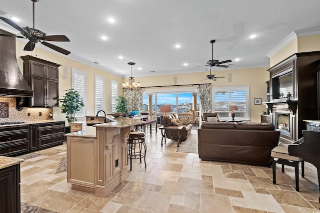 kitchen with pendant lighting, a breakfast bar, light stone counters, an island with sink, and decorative backsplash