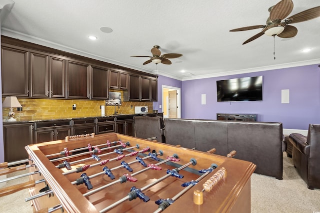 recreation room with ceiling fan, light colored carpet, ornamental molding, and sink