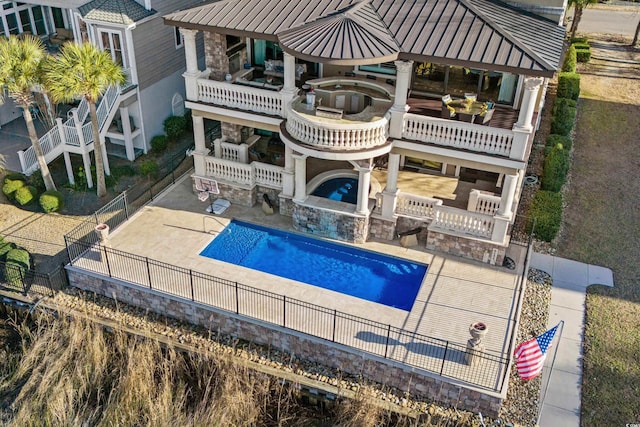 rear view of house with a gazebo, a balcony, a patio area, and a pool with hot tub