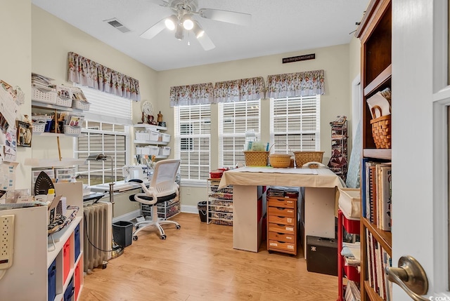 home office with a ceiling fan, visible vents, light wood-style flooring, and baseboards