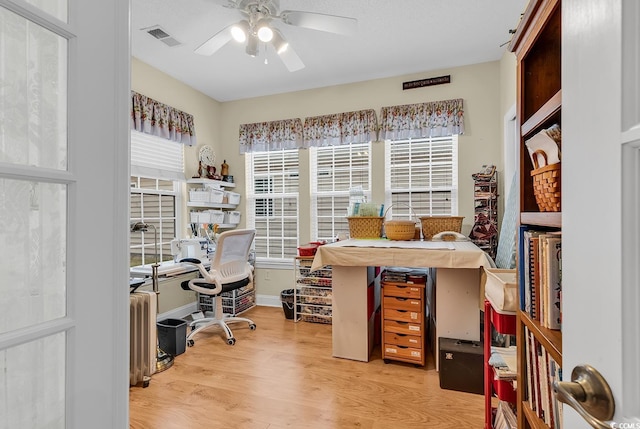 home office with light wood-style flooring, visible vents, ceiling fan, and baseboards