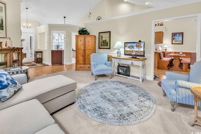 living area with high vaulted ceiling, ceiling fan with notable chandelier, crown molding, and light colored carpet