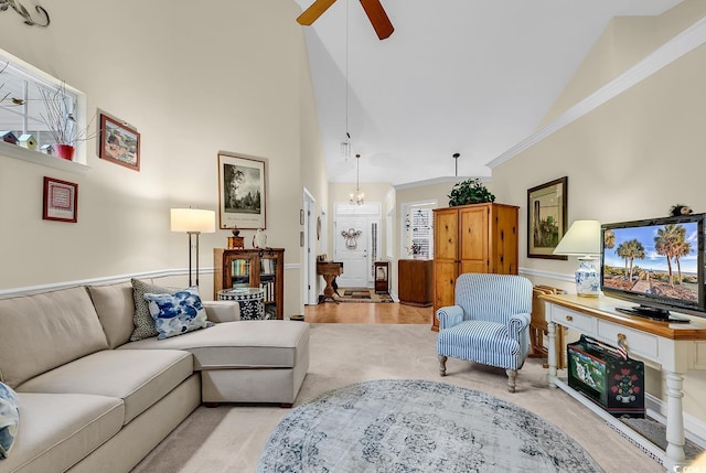 living room with high vaulted ceiling, light colored carpet, crown molding, and ceiling fan with notable chandelier