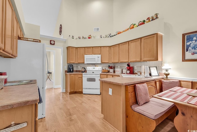 kitchen with light countertops, visible vents, a high ceiling, white appliances, and a peninsula