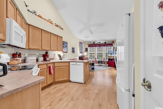 kitchen featuring light countertops, vaulted ceiling, light wood-type flooring, white appliances, and a peninsula