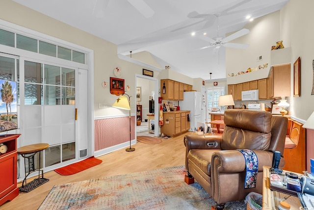 living room featuring light wood-type flooring, visible vents, a ceiling fan, and wainscoting