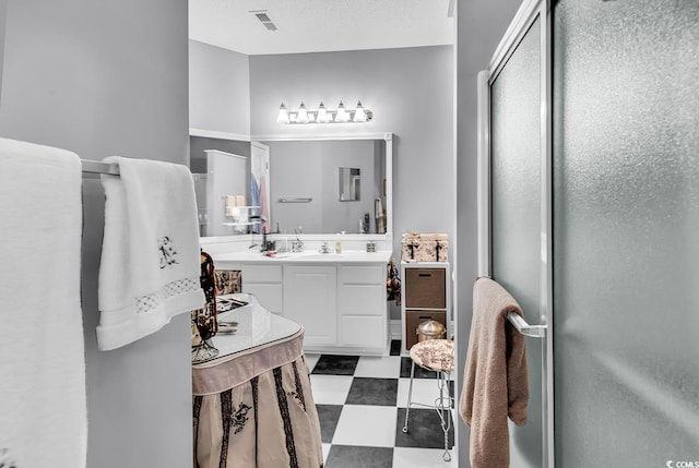 bathroom with a textured ceiling, vanity, visible vents, a shower stall, and tile patterned floors