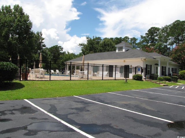 uncovered parking lot featuring fence and a community pool