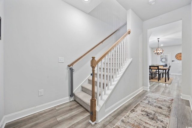 stairway featuring a notable chandelier and hardwood / wood-style flooring