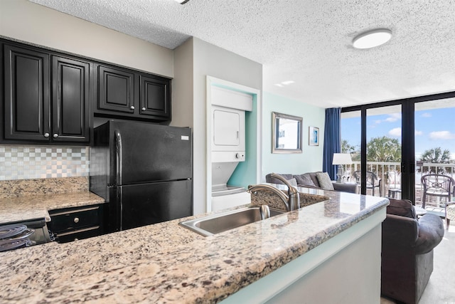 2700 N Ocean Blvd Unit 253, Myrtle Beach, SC 29577 - kitchen featuring freestanding refrigerator, stacked washer / drying machine, open floor plan, dark cabinets, and decorative backsplash