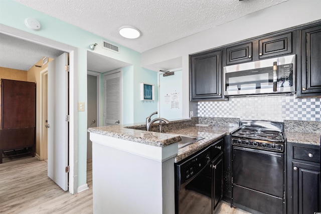 2700 N Ocean Blvd Unit 253, Myrtle Beach, SC 29577 - kitchen featuring black appliances, light wood-style flooring, a peninsula, a sink, and a textured ceiling