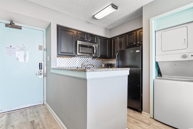 2700 N Ocean Blvd Unit 253, Myrtle Beach, SC 29577 - kitchen featuring stainless steel microwave, freestanding refrigerator, stacked washer and clothes dryer, light wood finished floors, and decorative backsplash
