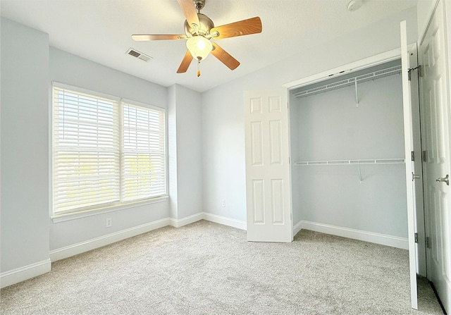 unfurnished bedroom with a closet, carpet, visible vents, ceiling fan, and baseboards