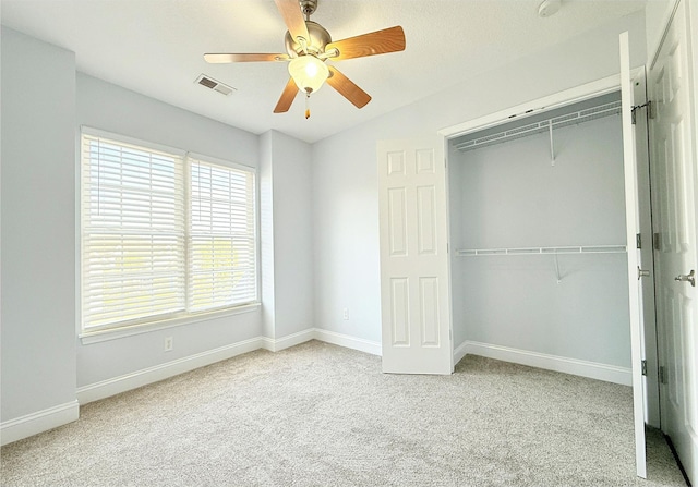 unfurnished bedroom with light carpet, ceiling fan, and a closet