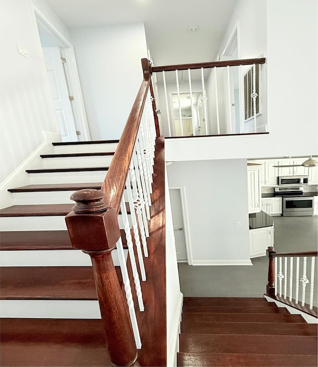 stairway featuring wood-type flooring and a high ceiling