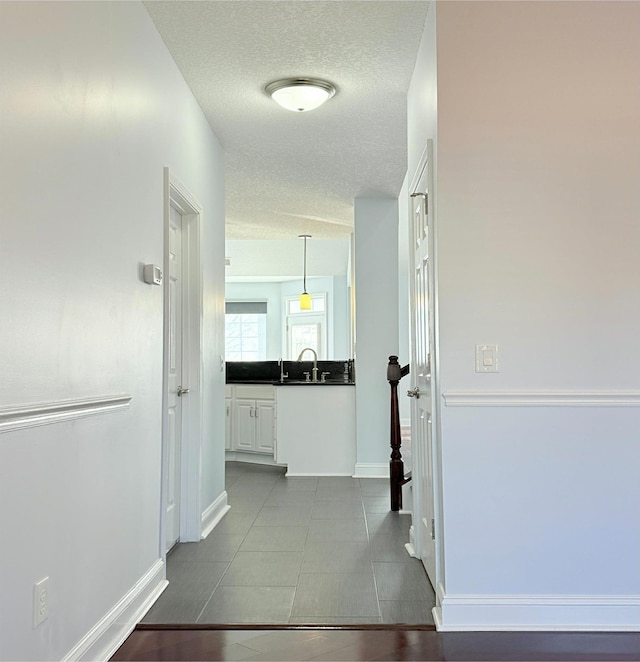 corridor with sink and a textured ceiling