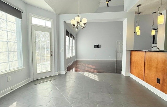 unfurnished dining area with an inviting chandelier, lofted ceiling, and dark tile patterned flooring